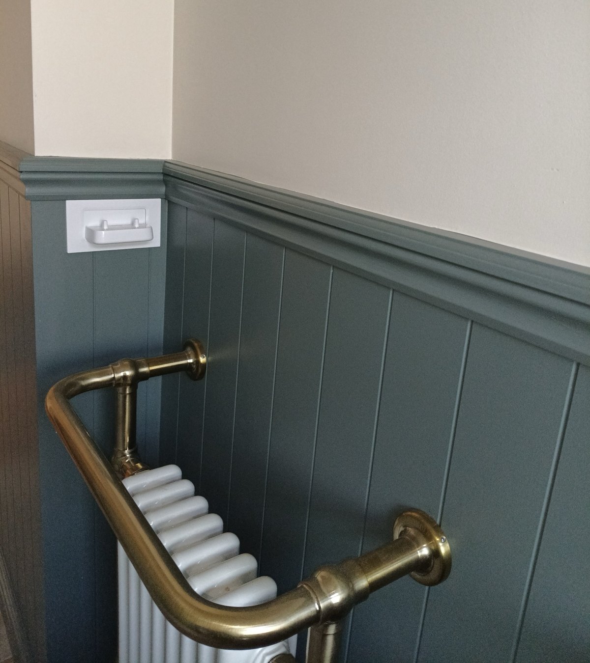 Deep green tongue-and-groove panelling with a moulded dado rail and brass towel rail